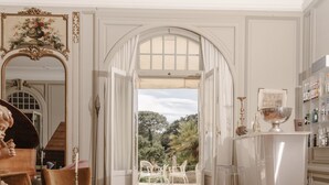 Une pièce spacieuse dotée d’un plancher en bois, d’un coin repas avec une table et des chaises, d’un bar avec des tabourets et d’une vue sur l’extérieur grâce à une arche ouverte.