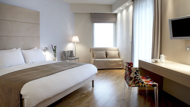 Una habitación de hotel moderna con una cama grande, un sofá, un televisor y un escritorio.