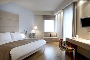 A modern hotel room with a large bed, a sofa, a TV, and a desk. -  Domotel Olympia (Thessaloniki)