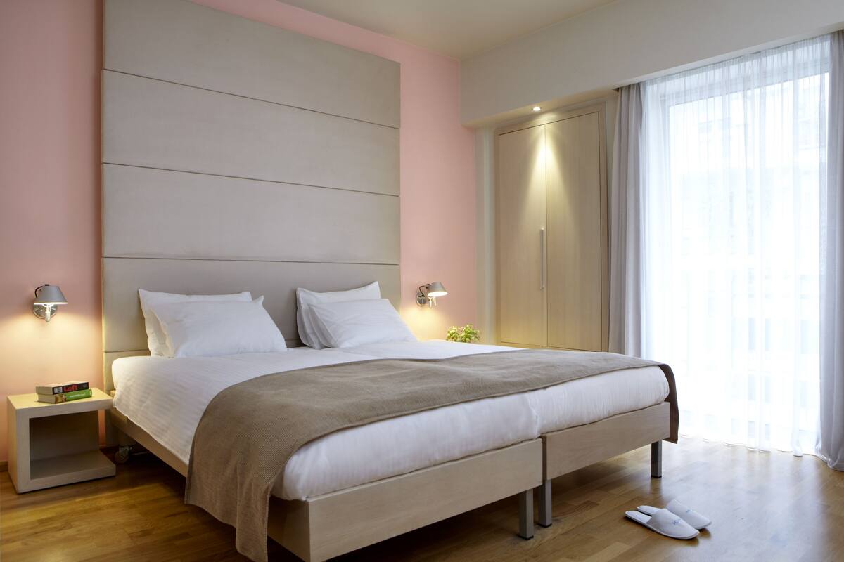 Un dormitorio moderno con una cama grande, lámparas de noche, una mesita de noche y un armario.