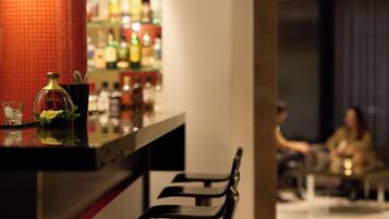 A bar area with a counter, a few chairs, and a blurred background of people.