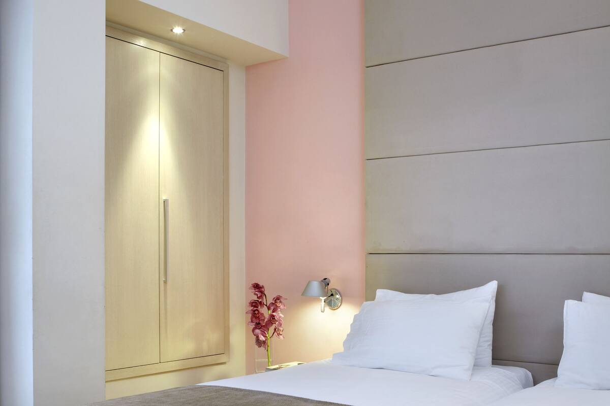 Un dormitorio moderno con una cama grande, un armario y una mesita de noche con lámpara.
