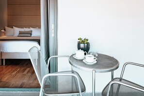 Een hotelkamer met een bed, een klein tafeltje met theepot en kopje, en een potplant.