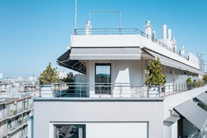 Un bâtiment moderne doté d’une terrasse sur le toit, d’un ascenseur à cage de verre et offrant une vue sur le paysage urbain.