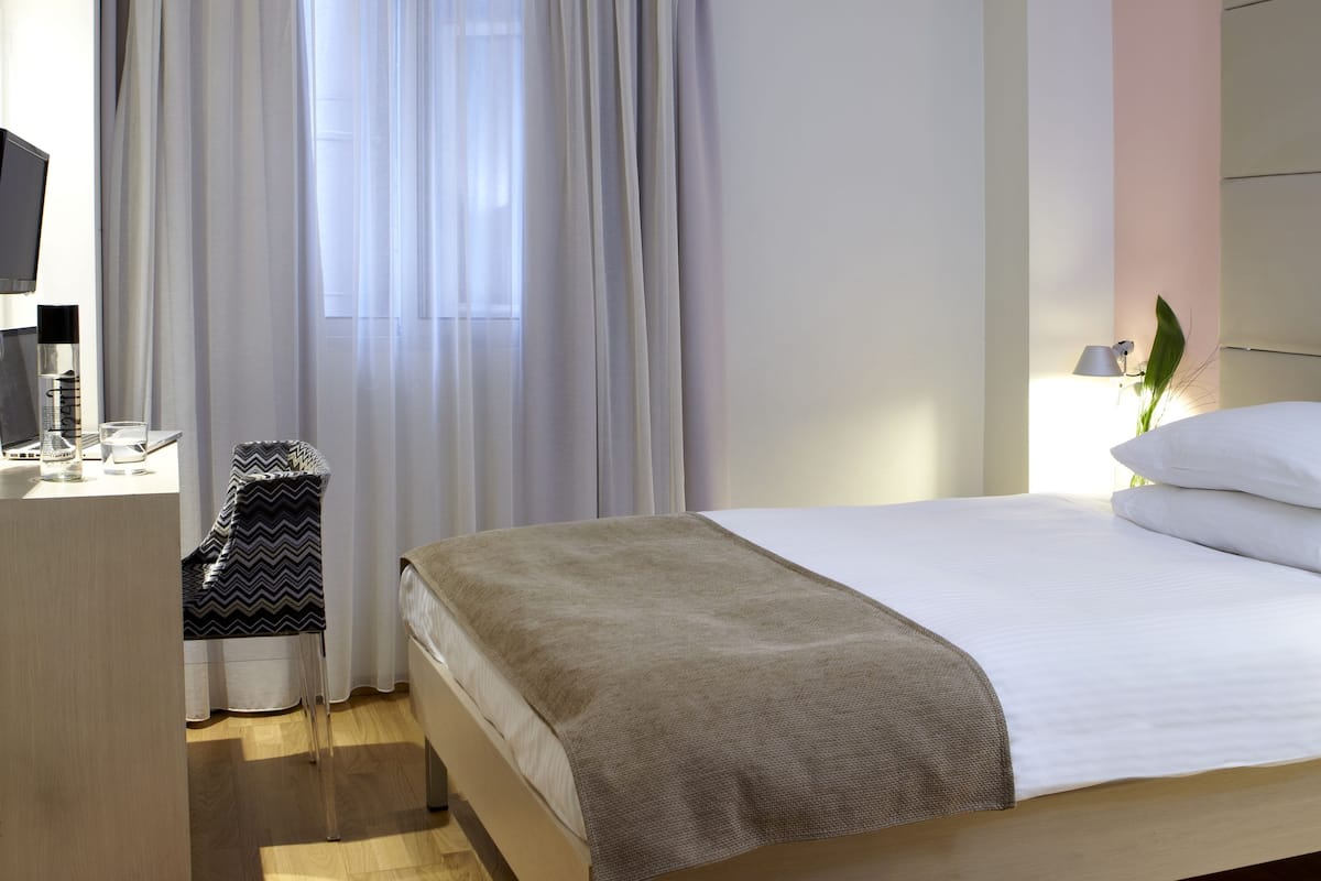 Una habitación de hotel moderna con una cama, un escritorio y una silla.