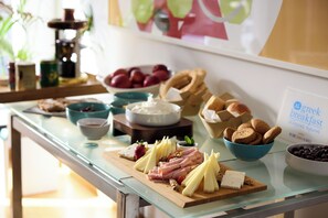 Une table de buffet proposant une variété d’aliments, notamment des fromages, des viandes, des fruits et des biscuits.