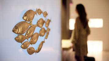 A room with a large fish sculpture on the wall and a person standing in the background.