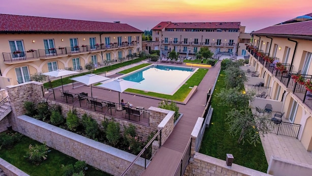 Um pátio com piscina, área de estar ao ar livre e vista para o pôr do sol.