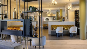 Um interior moderno com uma área de estar central, uma lareira e uma cozinha ao fundo.