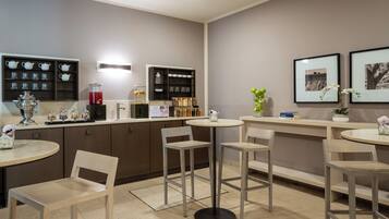 Un café moderno con una zona de bar, asientos y una exhibición de juegos de té y frascos.