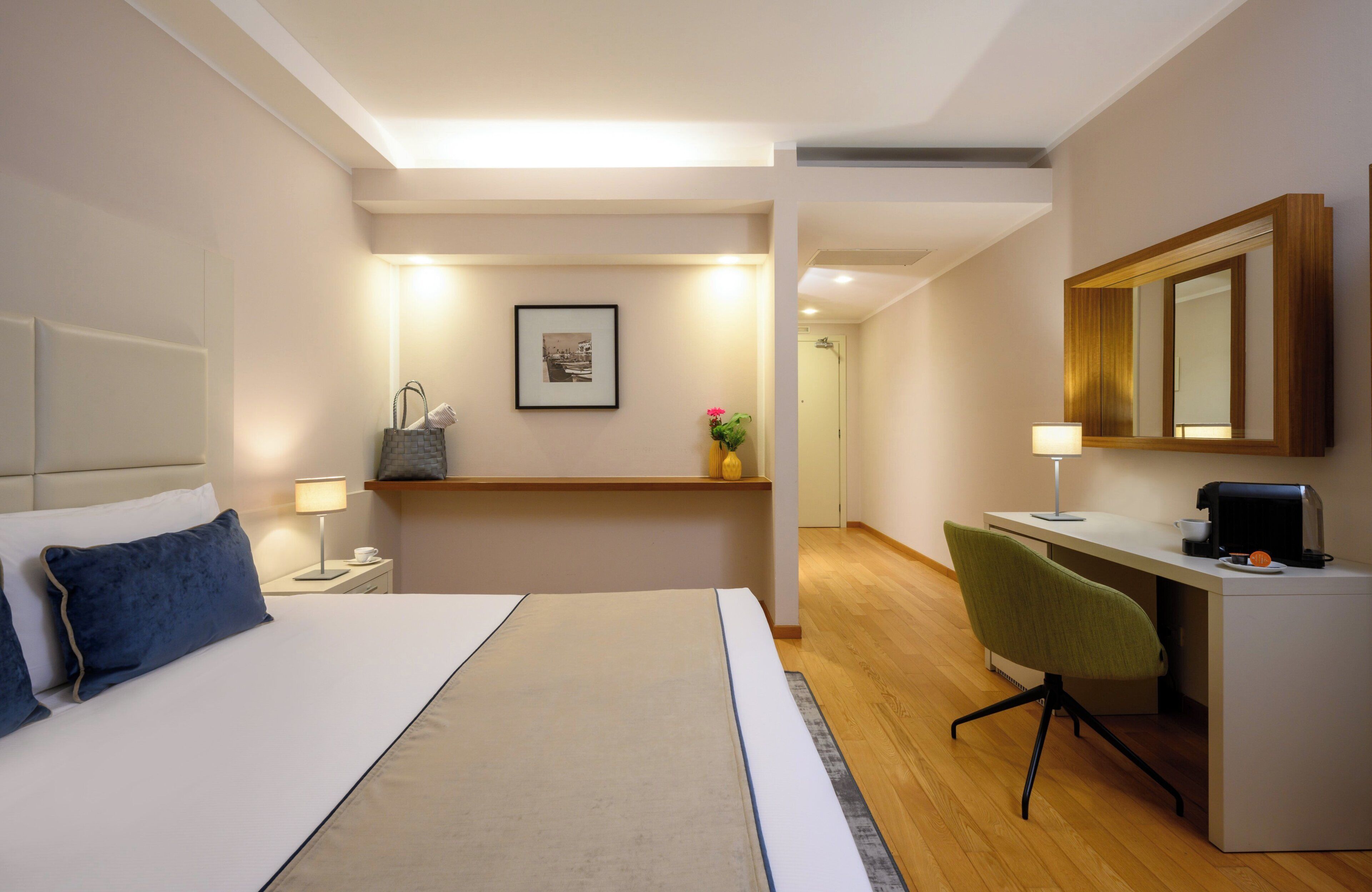 Une chambre d’hôtel avec un lit, un bureau, une chaise et un miroir.