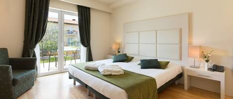 Una habitación de hotel moderna con una cama grande, un escritorio, una silla y un balcón con cortinas.