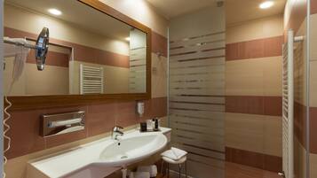 Un baño moderno con un espejo grande, dos lavamanos, un perchero para toallas y un box de ducha de vidrio.