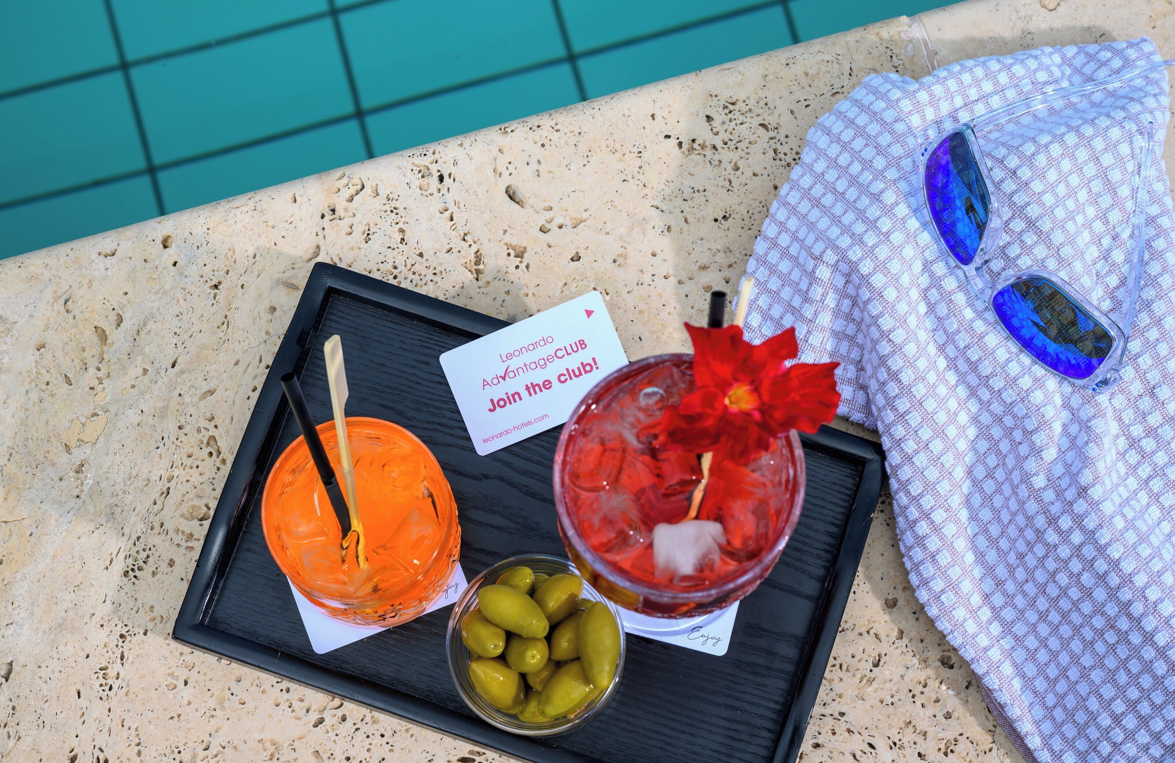 A tray with two drinks, a card, and a bowl of olives.