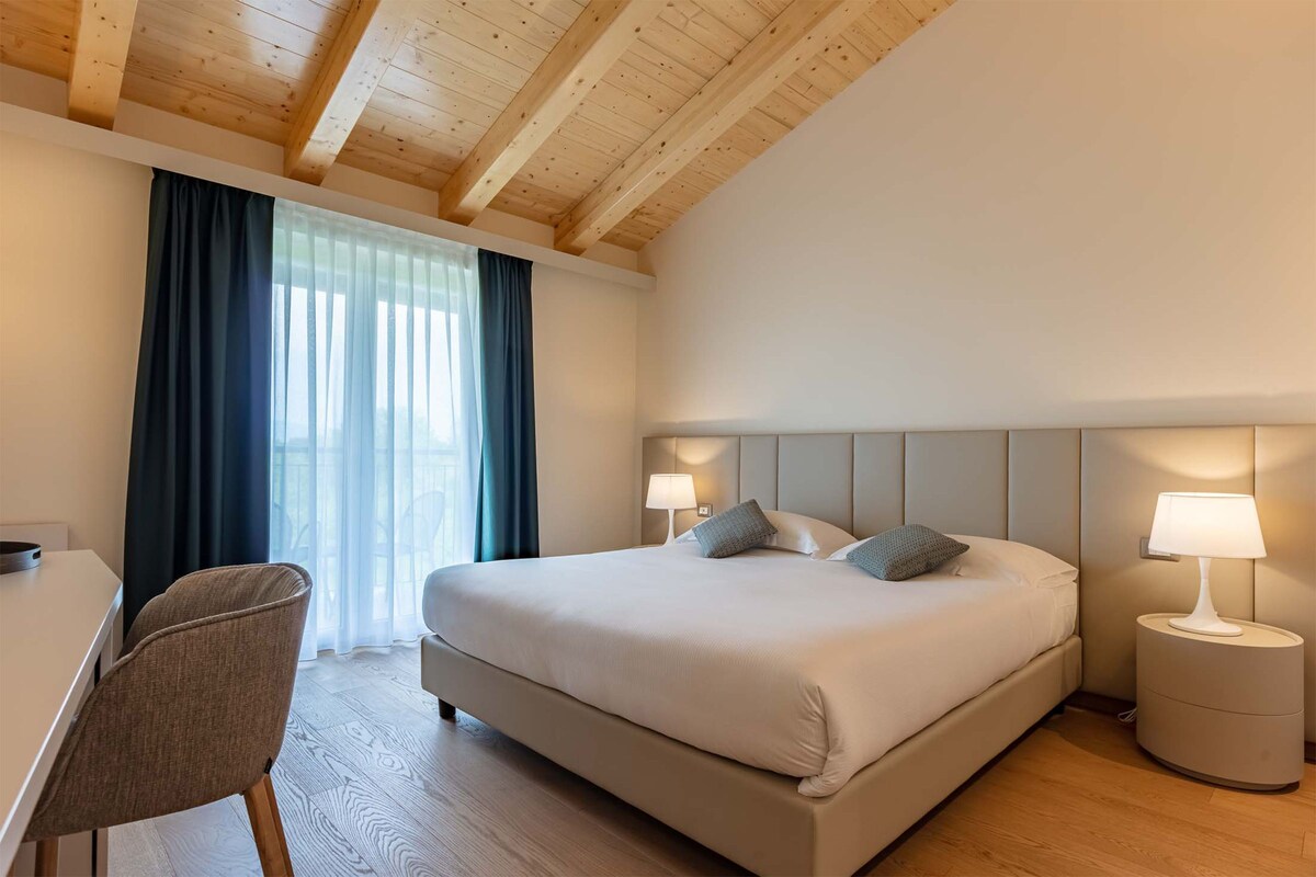 Habitación de hotel moderna con una cama grande, lámparas de noche, un escritorio y una silla.