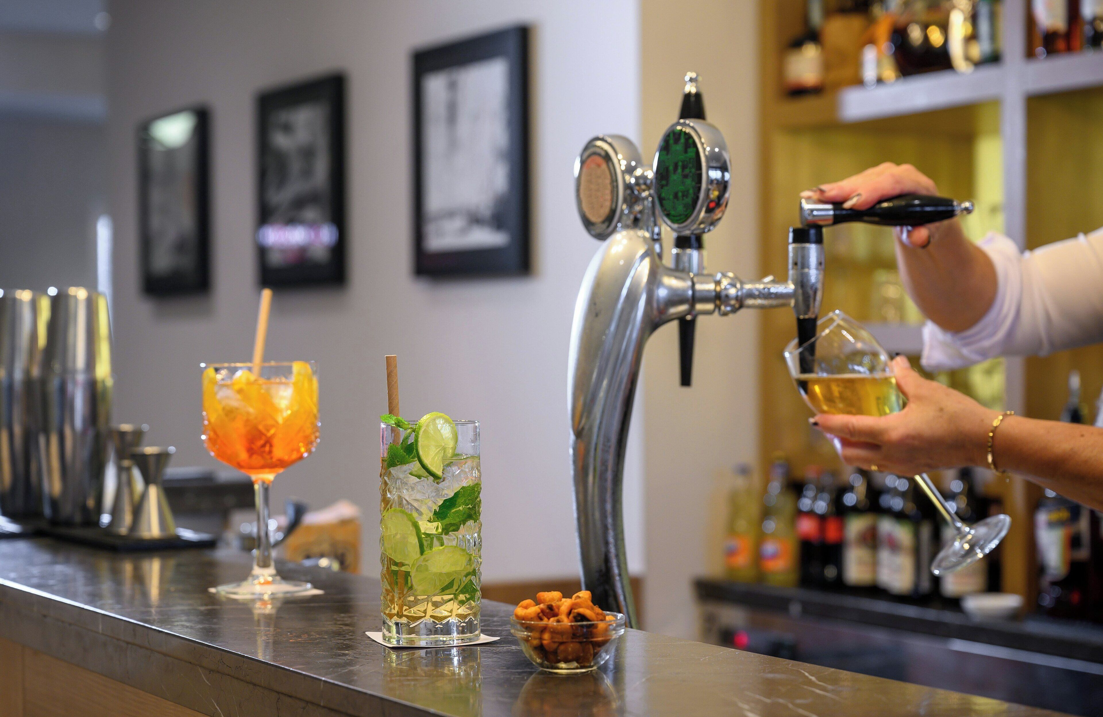 Un bar avec un comptoir, un cocktail et un verre de bière.