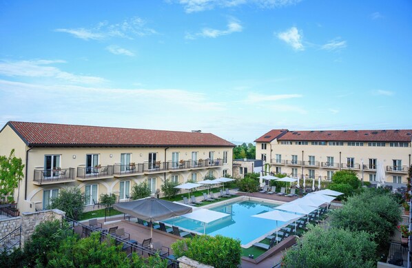 A hotel with a swimming pool, multiple balconies, and outdoor seating areas. - Leonardo Hotel Lago di Garda – Wellness and Spa (Lazise)