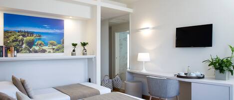 Una habitación de hotel moderna con dos camas, un escritorio con silla, un televisor de pantalla plana y un cuadro de paisaje grande en la pared.