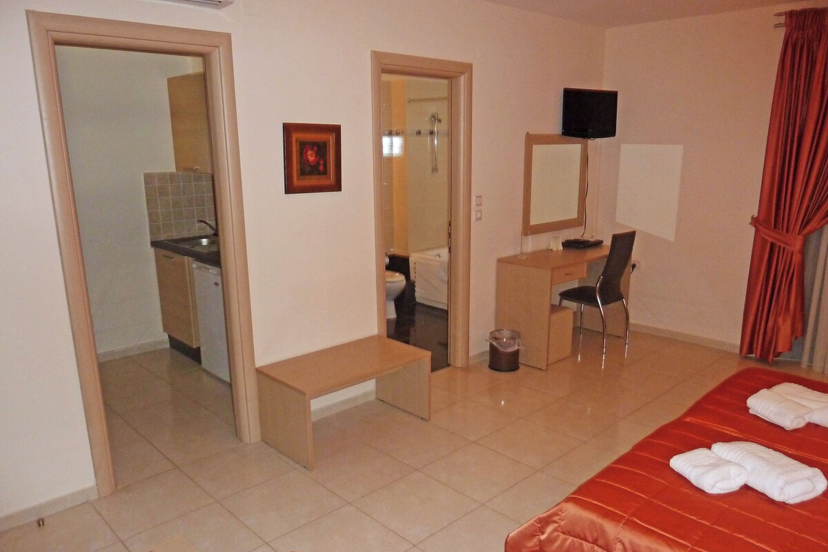 Una habitación de hotel con cama, escritorio, silla, baño y televisión.