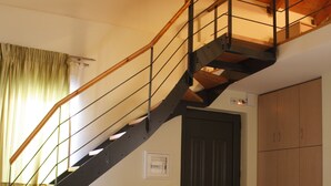 A bedroom with a bed, a chair, a desk, a wardrobe, and a staircase.
