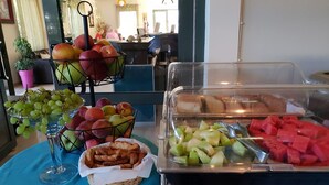 A buffet with fruits, bread, and pastries.
