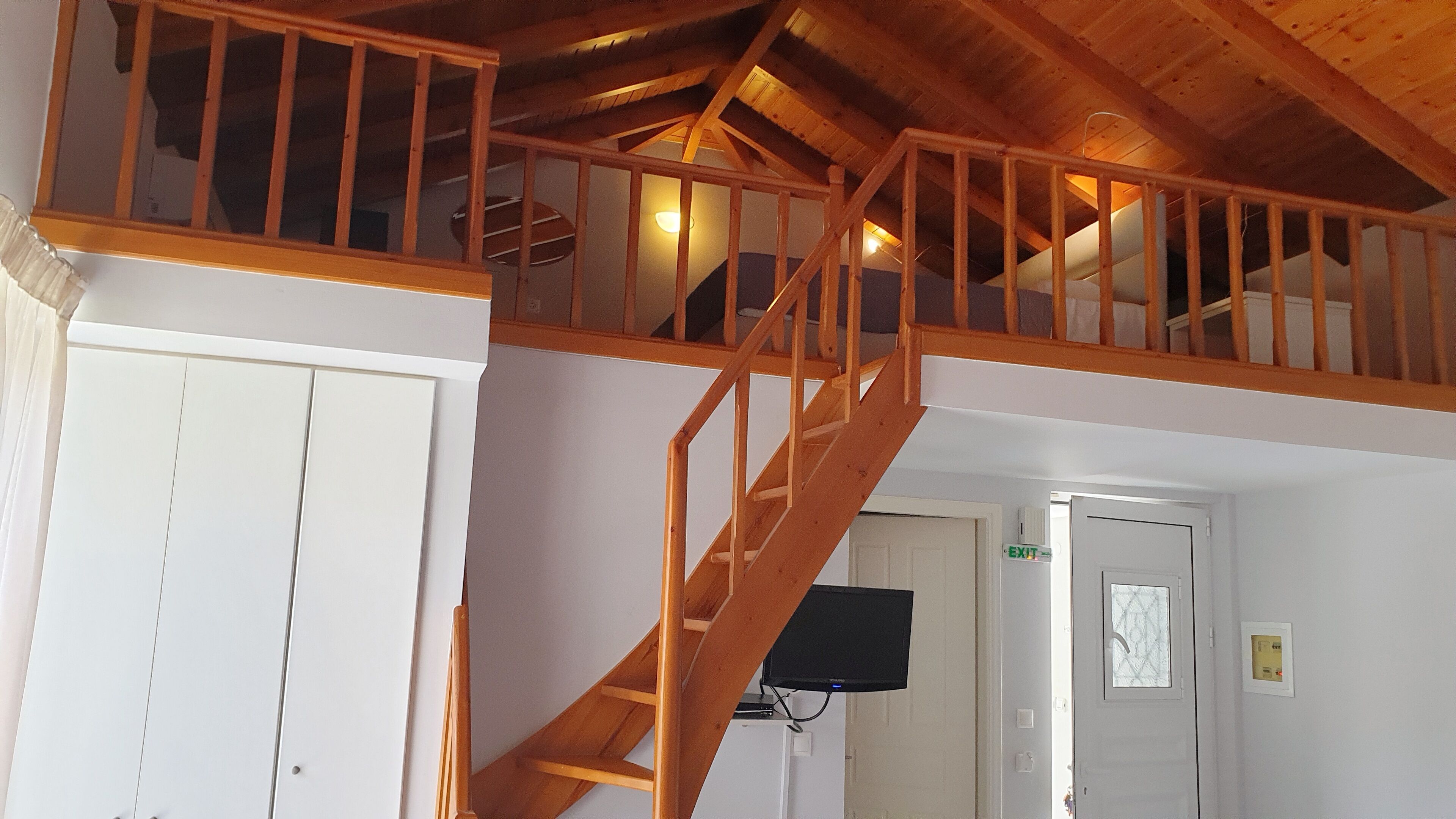 A wooden staircase leading to an upper level with a view of the interior.