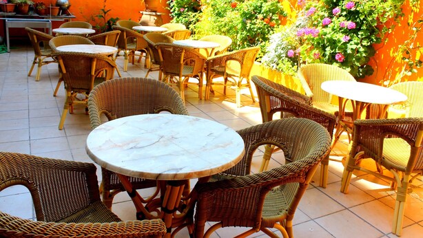 An outdoor patio with wicker furniture and a tiled floor. - Savoy City Hotel (Rhodes)