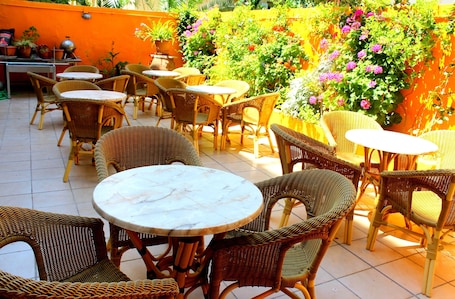 An outdoor patio with wicker furniture and a tiled floor.
