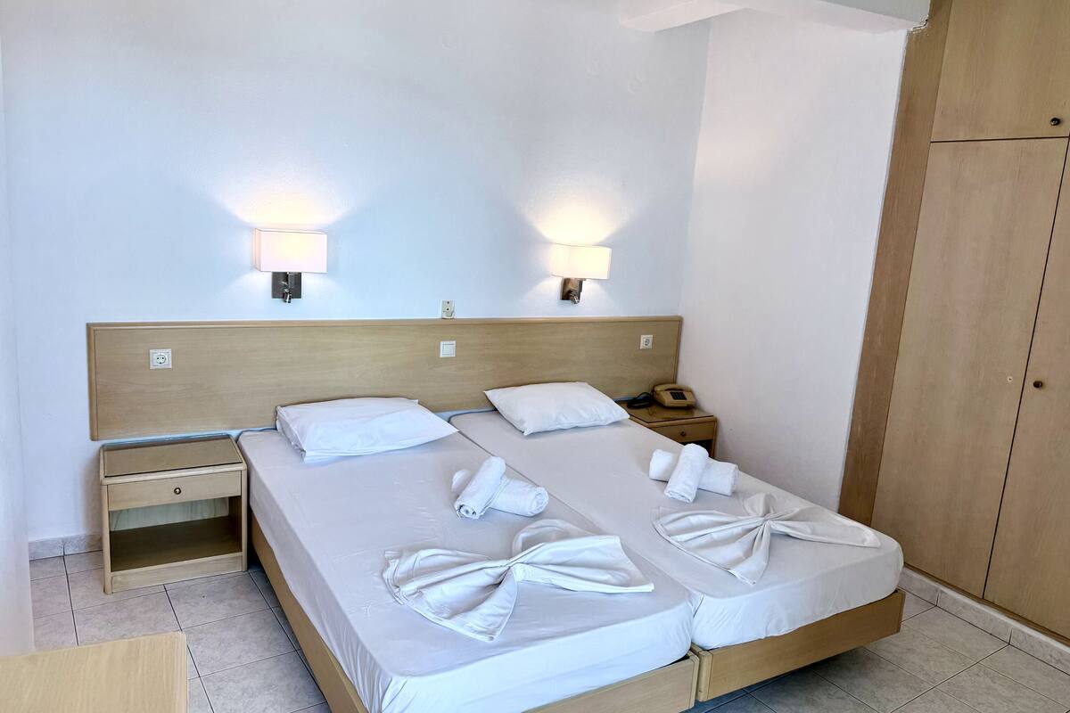 Una cama doble con dos almohadas y una mesita de noche con lámpara y teléfono.