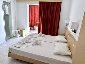 A hotel room with a bed, a chair, a small table, and a bathroom door. - Savoy City Hotel (Rhodes)