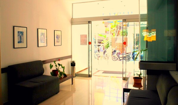 A reception area with a sofa, a coffee table, and a potted plant. - Savoy City Hotel (Rhodes)