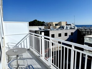 A balcony with a table and chairs, overlooking a marina with boats and buildings. - Savoy City Hotel (Rhodes)