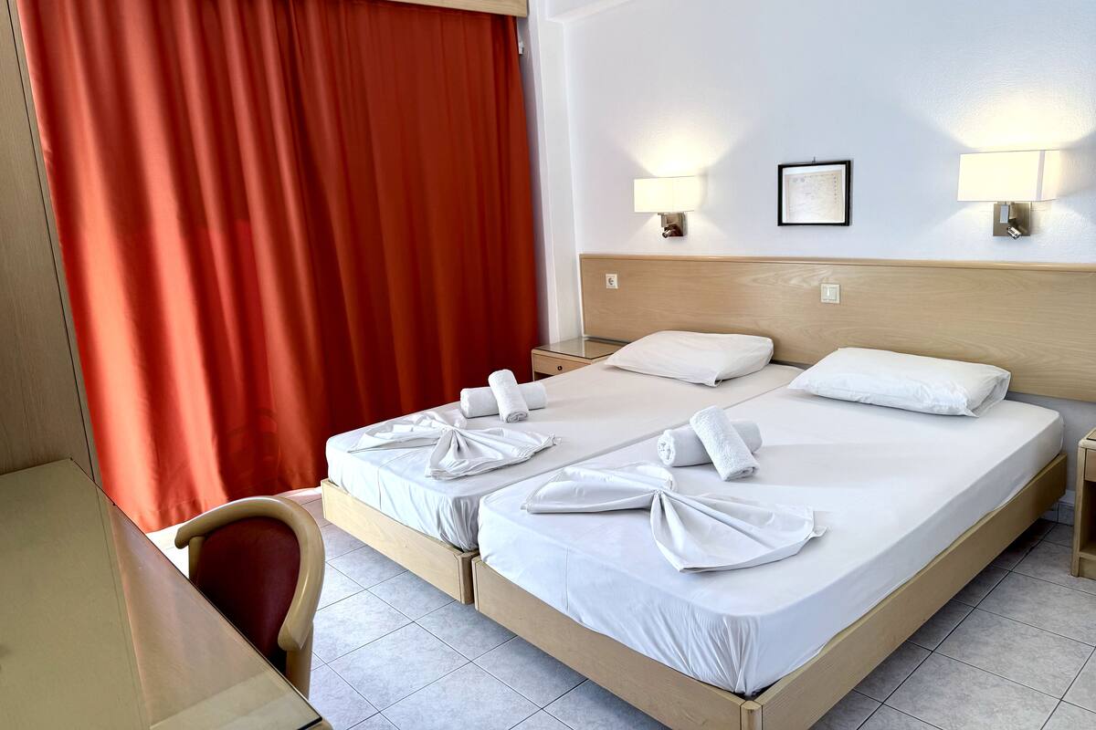 Habitación de hotel con dos camas, un escritorio y una silla.