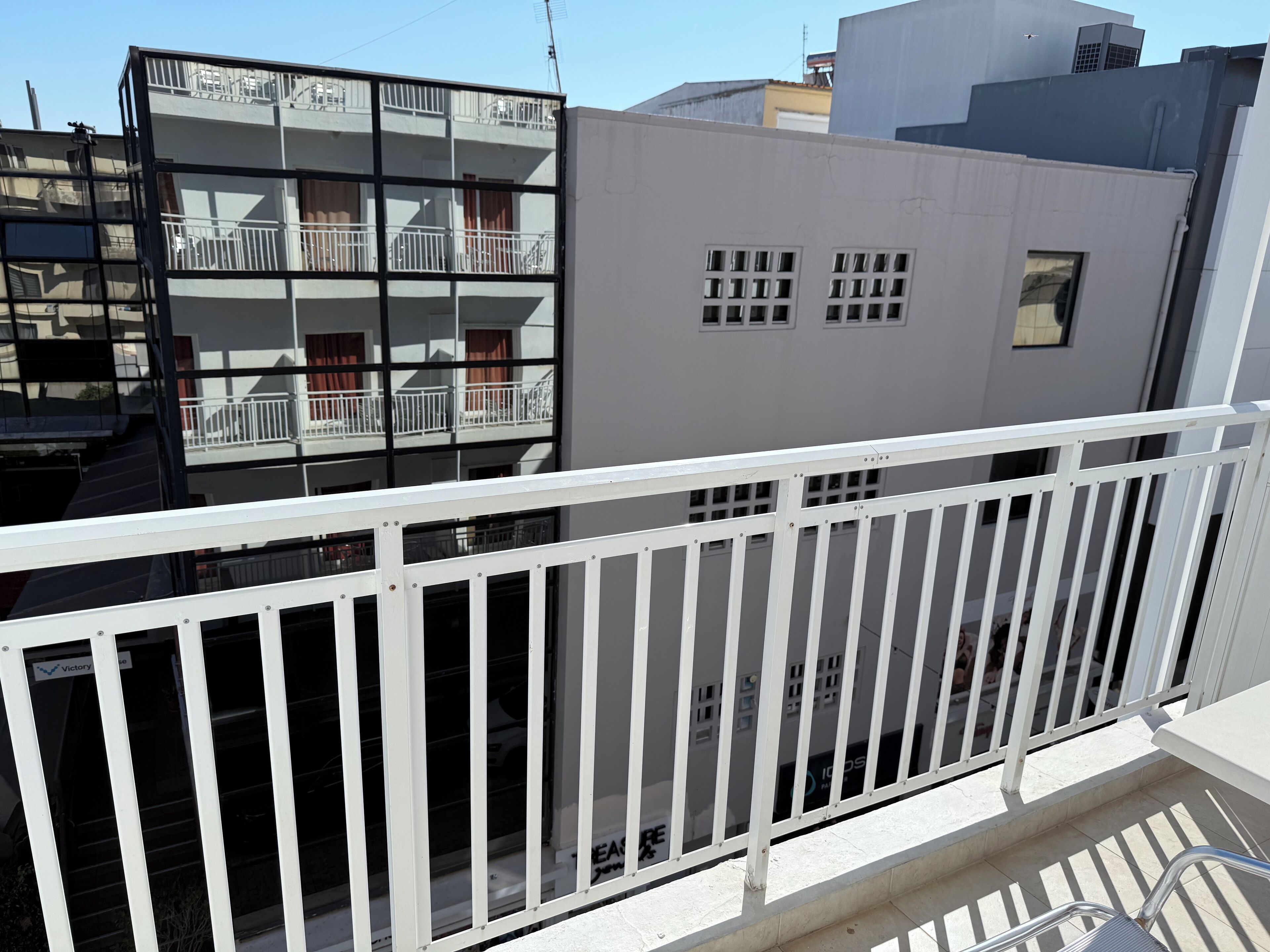 A balcony with white railings overlooking a building with multiple balconies and windows.