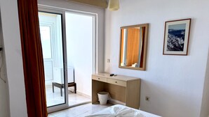 A hotel room with a bed, a desk, a chair, a mirror, and a picture on the wall. - Savoy City Hotel (Rhodes)