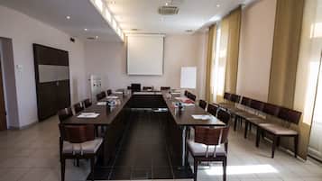 A conference room with a long table, chairs, a whiteboard, and a projector screen.