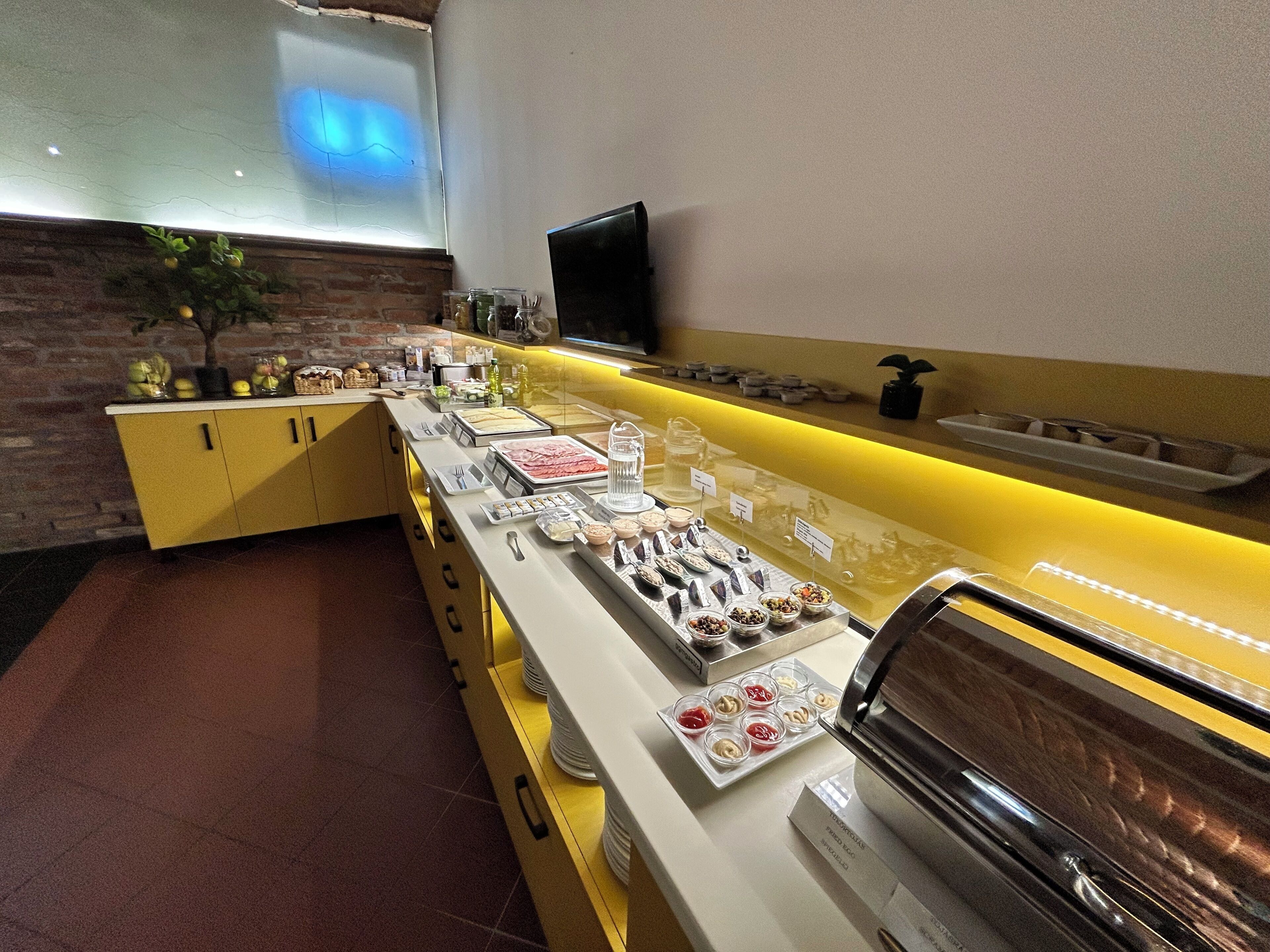 A buffet setup with various food items and a television on the wall.