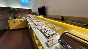 A buffet setup with various food items and a television on the wall.