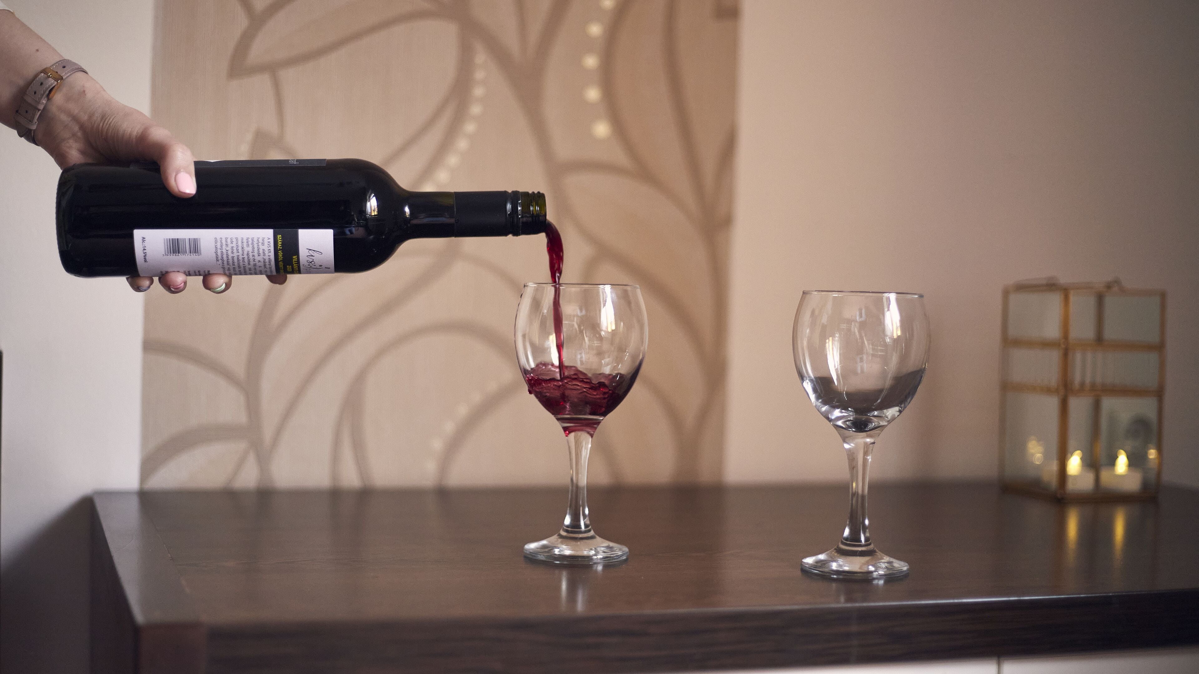 Una persona sirviendo vino en una copa sobre una mesa de madera.