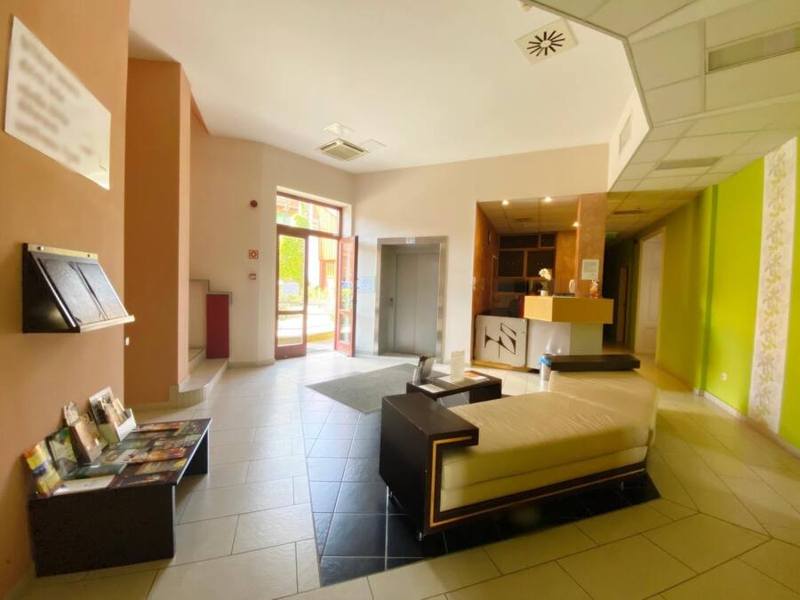 Habitación de hotel con cama, escritorio, mesita y zona de recepción con mostrador y ventana.