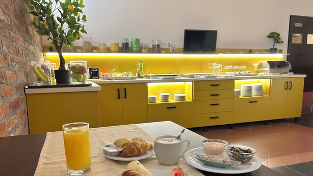 A breakfast setup with croissants, eggs, tomatoes, and juice on a table. - Boutique Hotel Sopianae (Pecs)