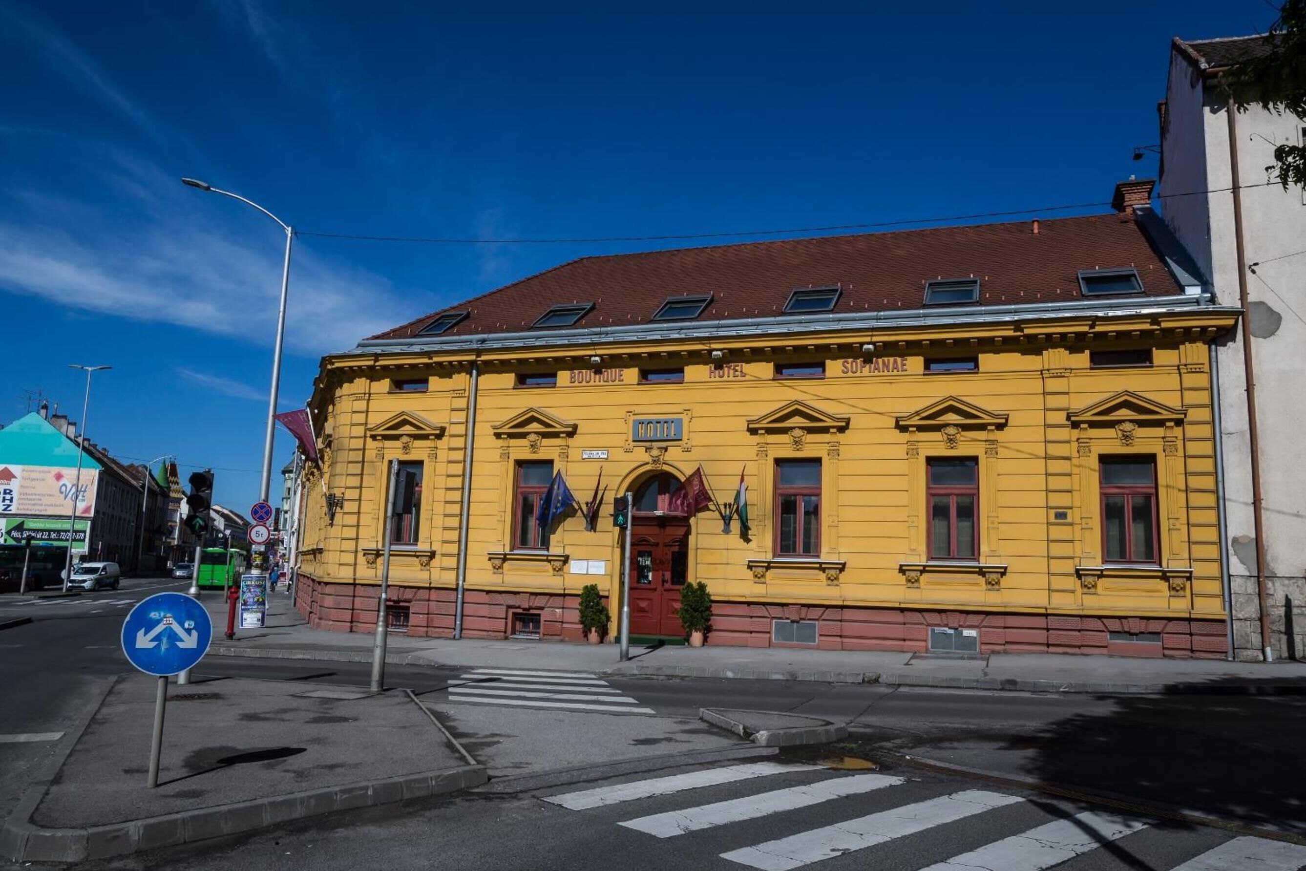 A yellow building with a red roof, labeled as a hotel.