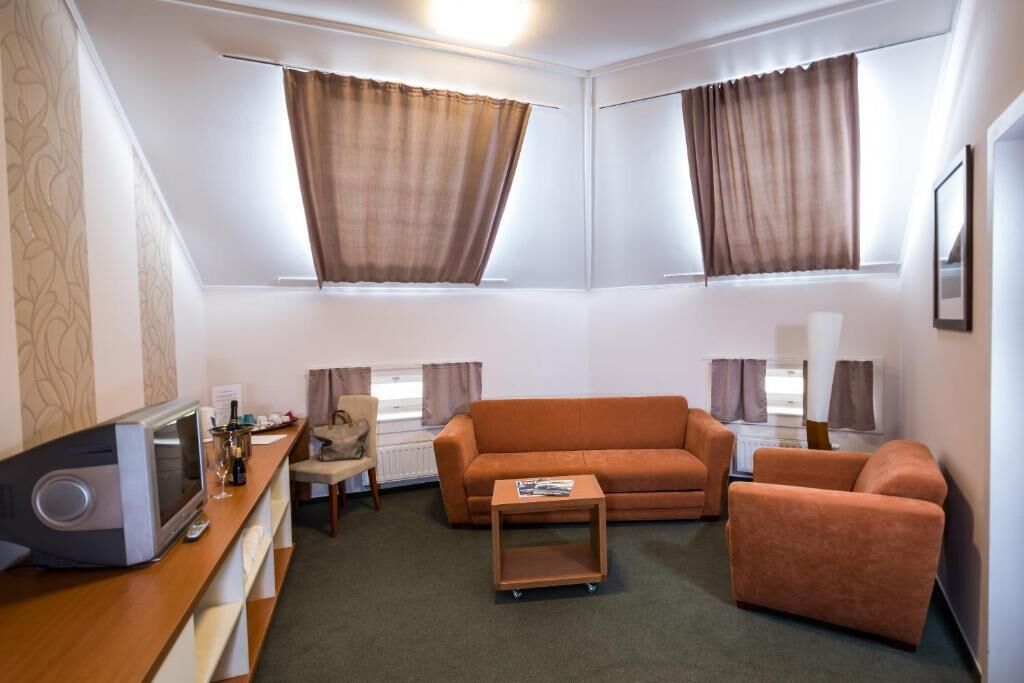 Un salon de taille réduite comprenant un canapé, des fauteuils, une table basse et un téléviseur.