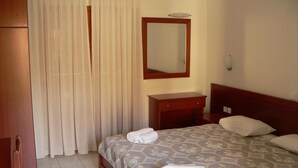 A hotel room with a bed, a bedside table, a mirror, a wardrobe, and a curtain.