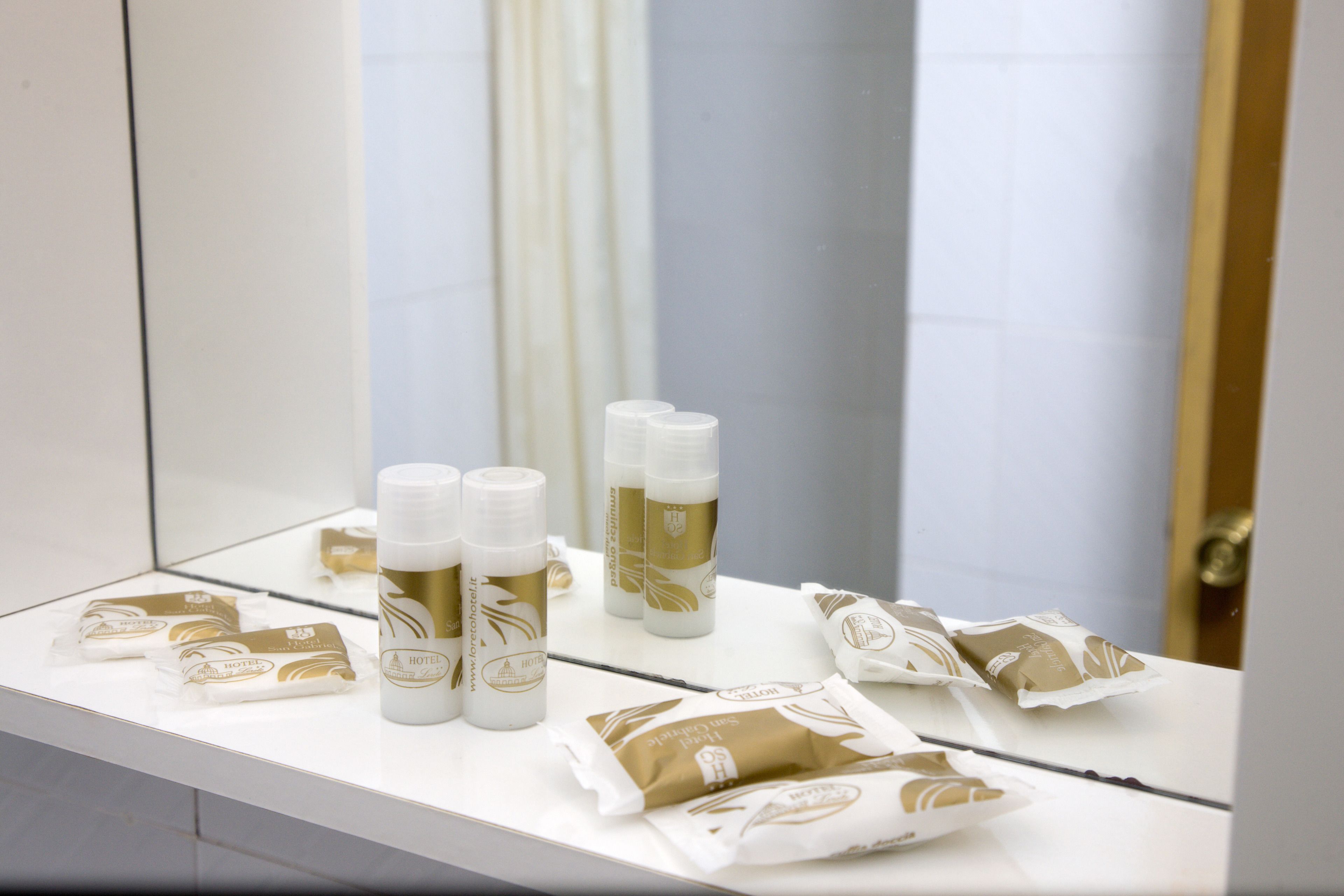 A bathroom counter with toiletries and a mirror reflecting the room.