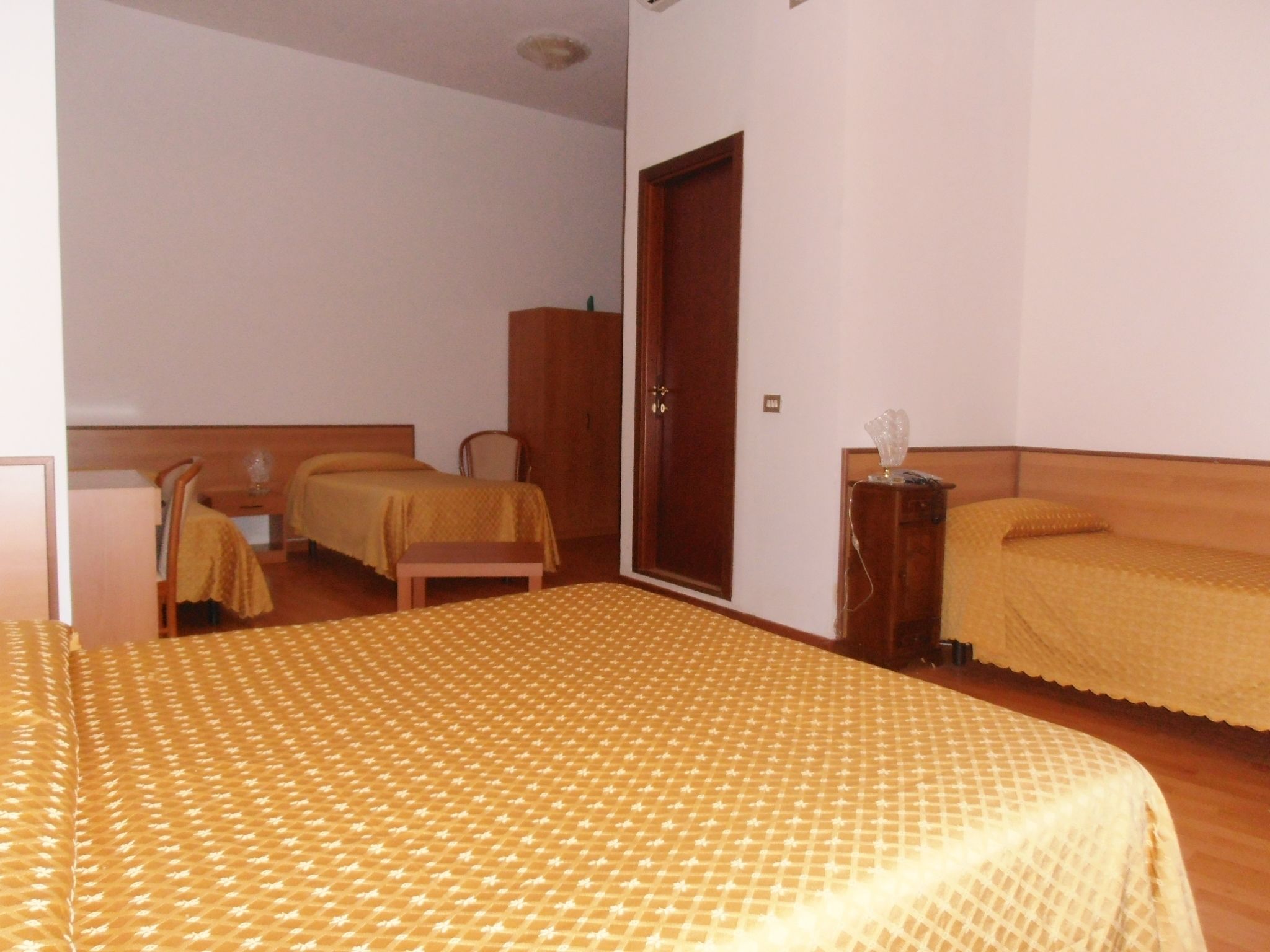 A hotel room with two beds, a wooden wardrobe, and a small table.