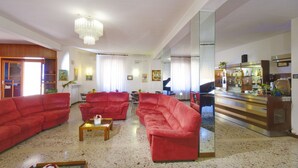 A spacious living room with red sofas, a wooden coffee table, and a piano. - San Gabriele (Loreto)