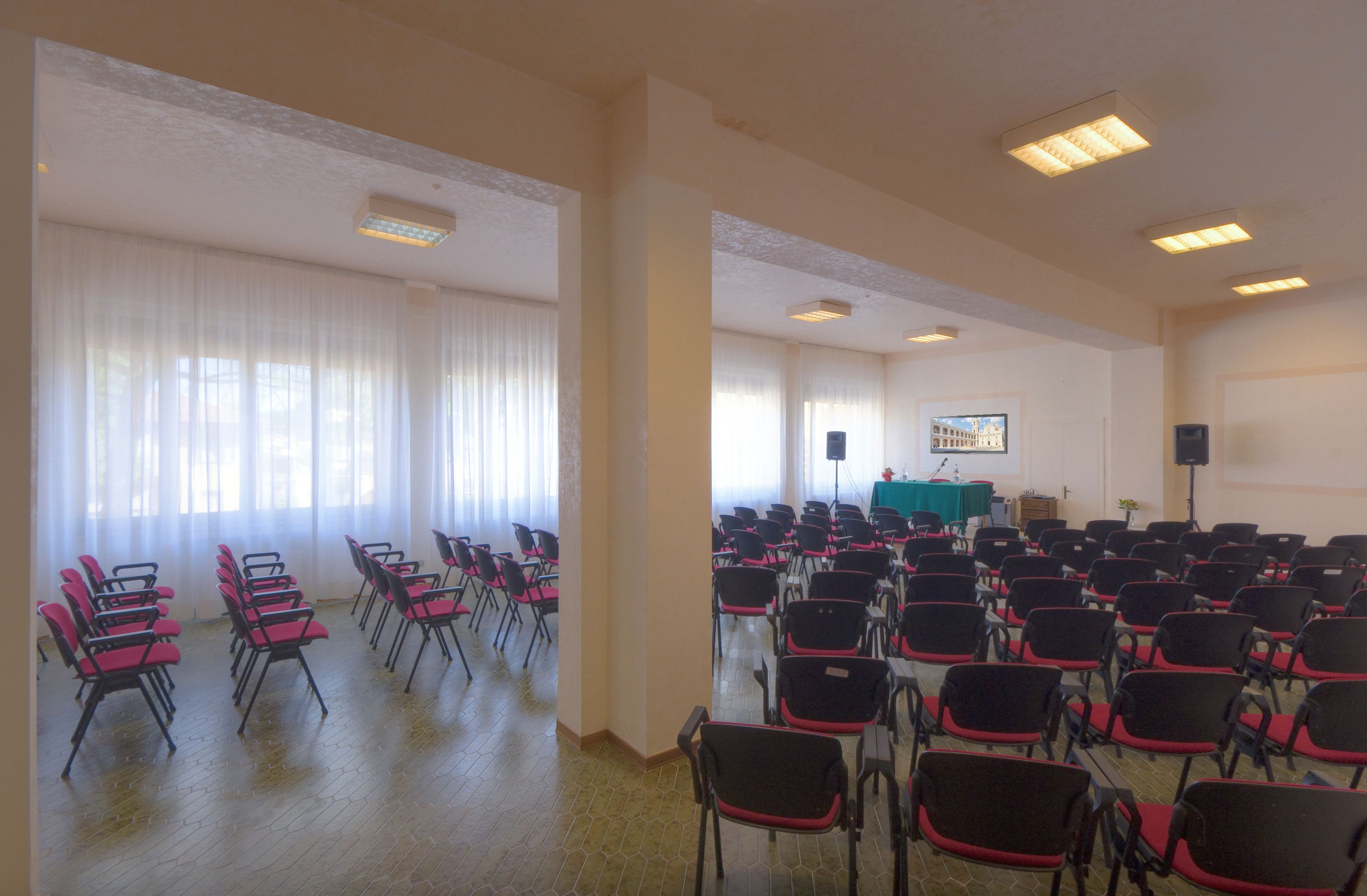 A conference room with rows of chairs, a podium, and a projector screen.