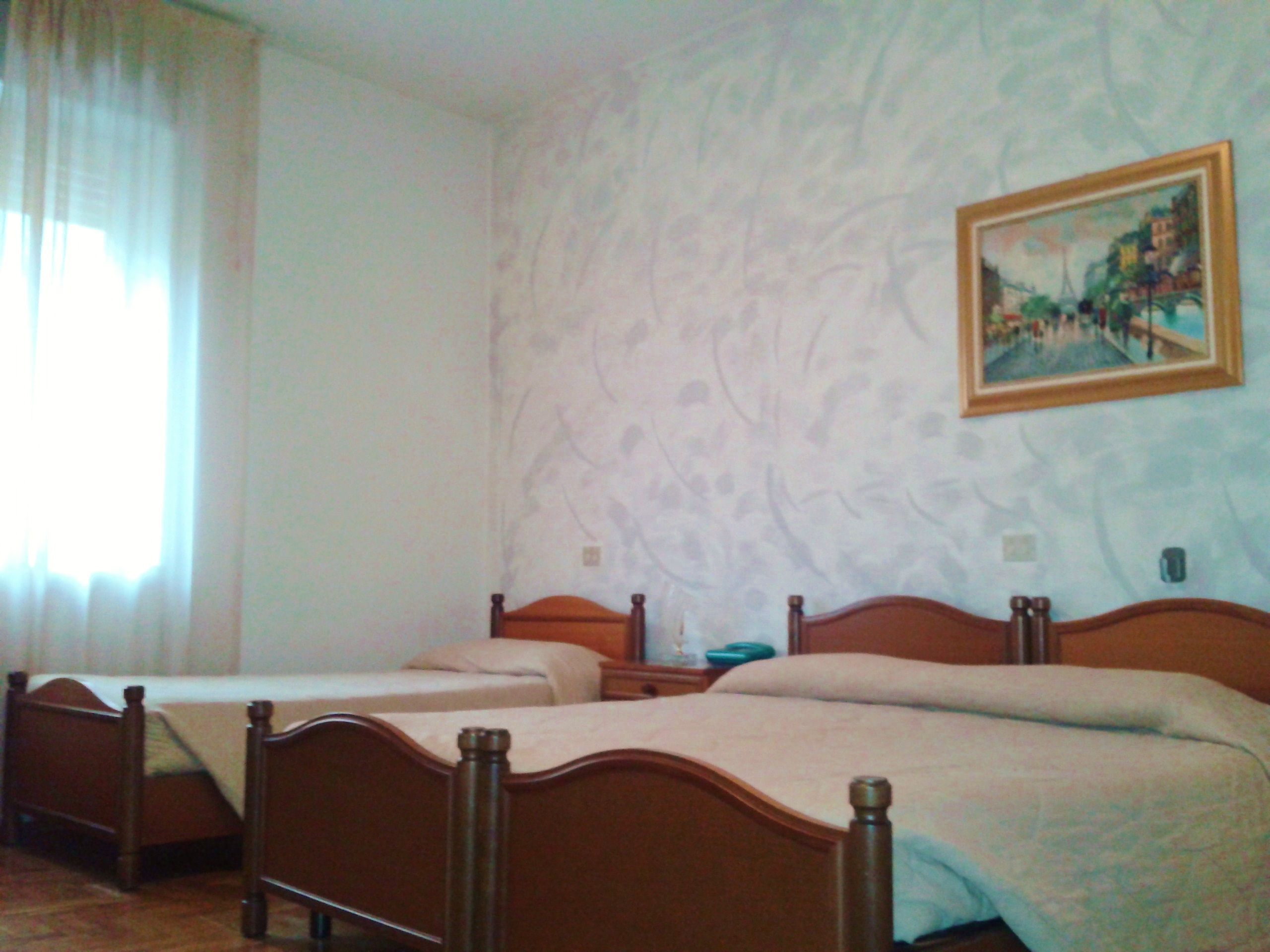 A bedroom with two wooden beds, a nightstand, and a painting on the wall.