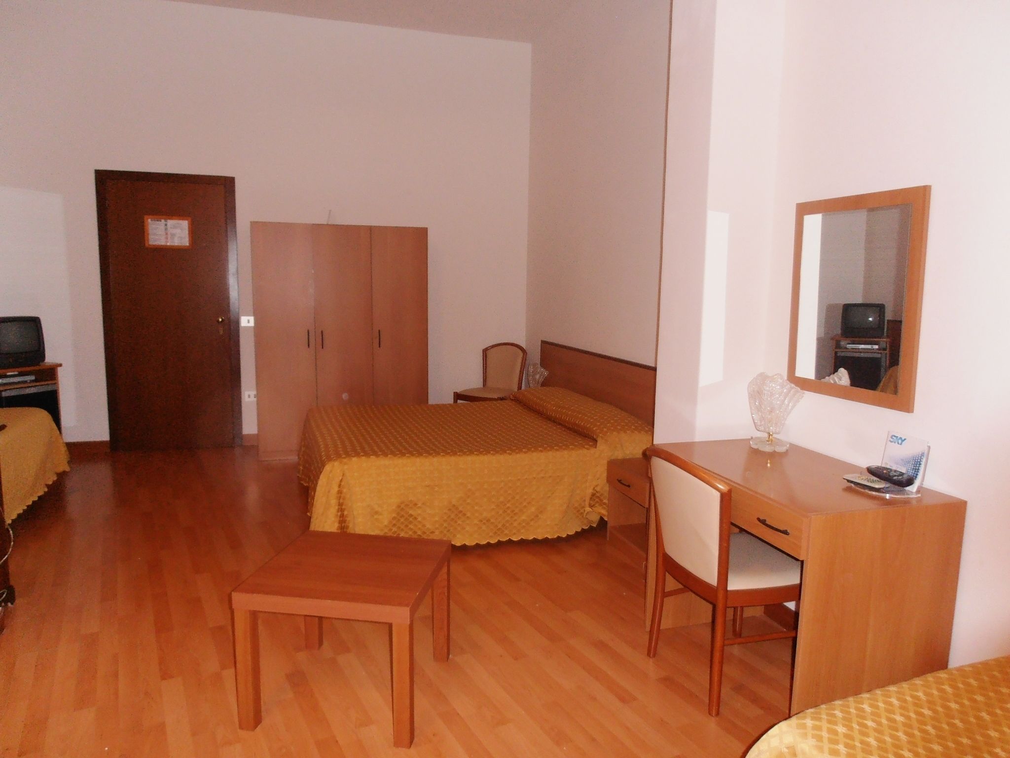 A small, tidy room with a bed, a desk, a chair, and a wardrobe.